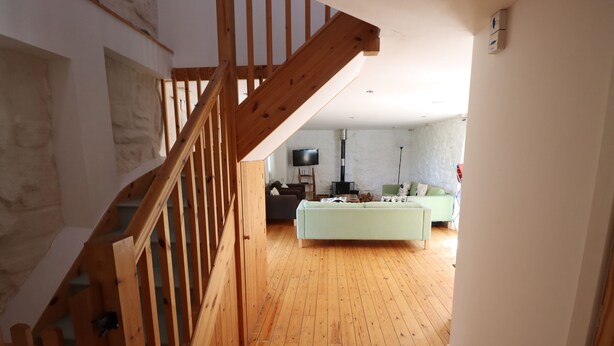 Una escalera de madera que lleva a una sala de estar con un sofá y un televisor.