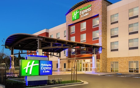 A Holiday Inn Express & Suites hotel with a modern architectural design, featuring a prominent entrance and signage.