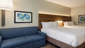 A hotel room with a large bed, a blue sofa, and a framed abstract art piece on the wall. - Holiday Inn Express & Suites Hayward - Castro Valley by IHG (Hayward)