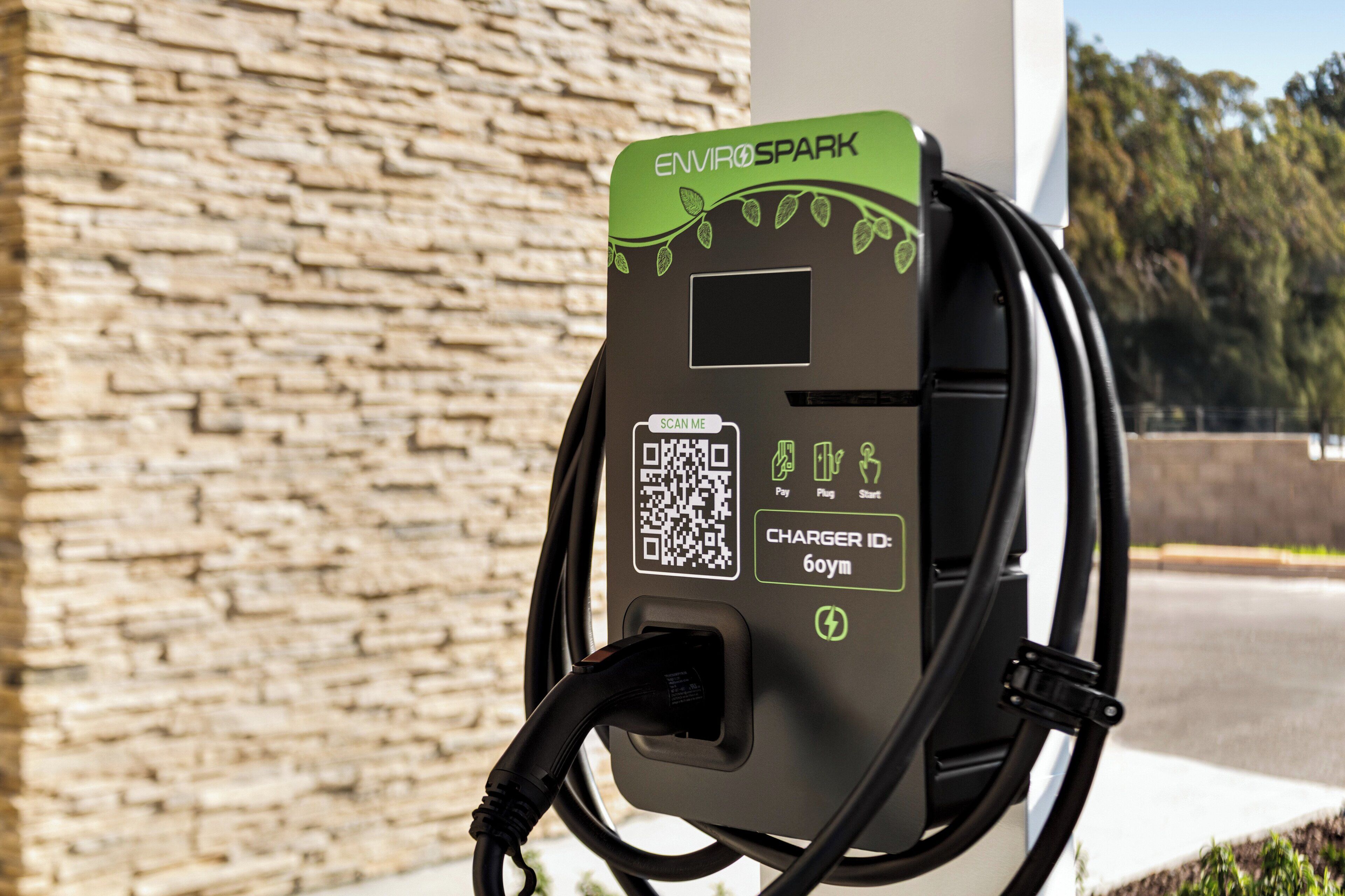 An EnviroSpark electric vehicle charging station with a QR code, payment icons, and a charger ID.