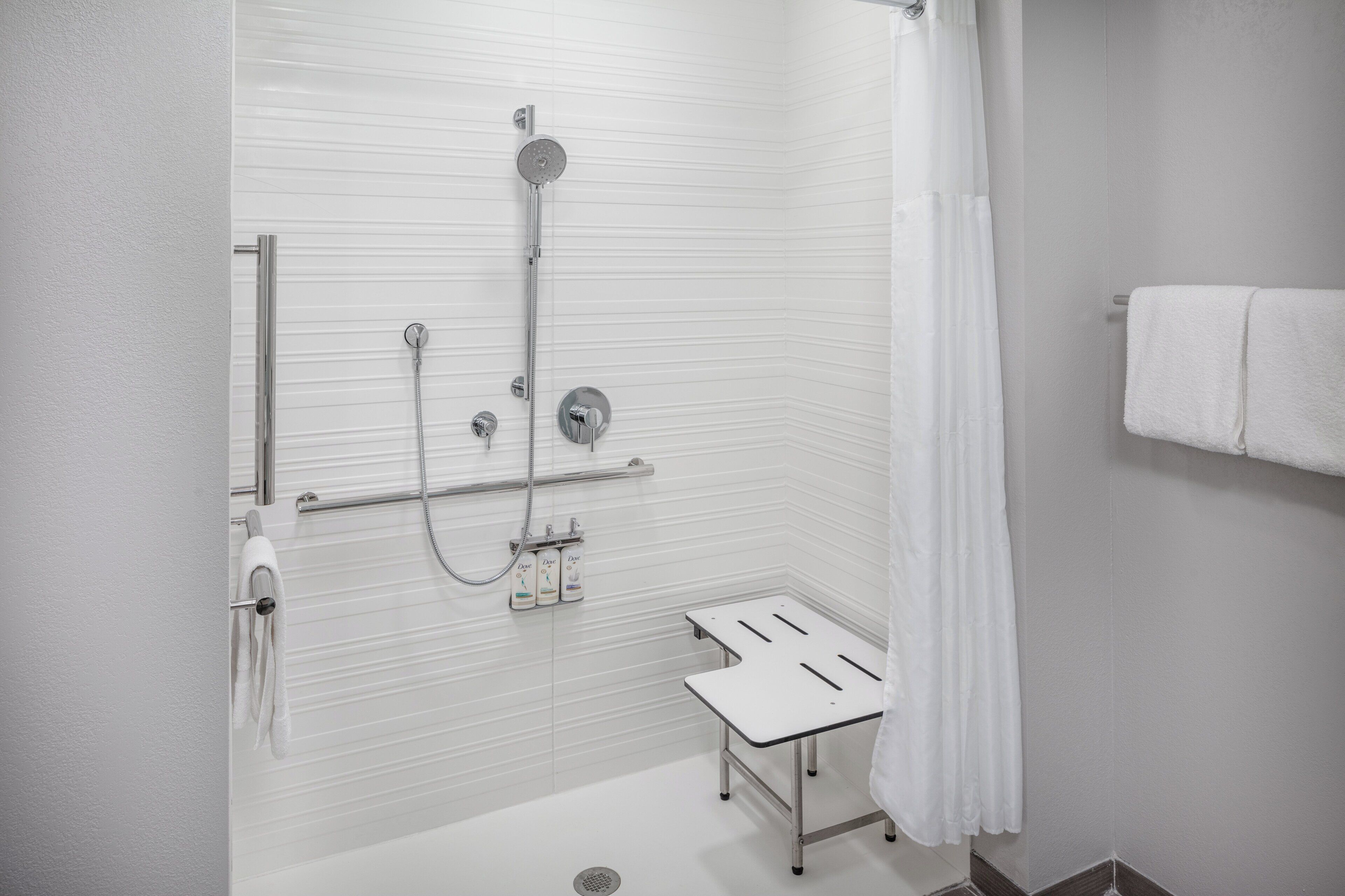 Une douche moderne dotée d’un pommeau de douche à main, d’un robinet mural et d’un espace de douche délimité par des parois en verre.
