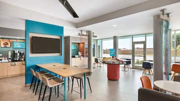 A modern dining area with a long table, chairs, and a coffee station.