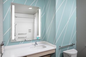 A bathroom with a white sink, a mirror, a towel rack, and a toilet. - avid hotel North Platte by IHG (North Platte)