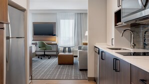 A modern hotel room with a kitchenette, a dining area, and a seating area with a TV. - Staybridge Suites Port Elgin by IHG (Saugeen Shores)