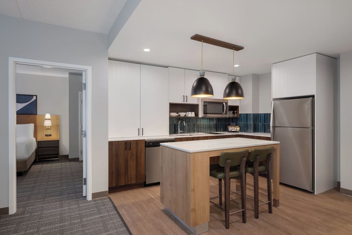 A modern kitchen with a central island, stainless steel appliances, and pendant lighting.