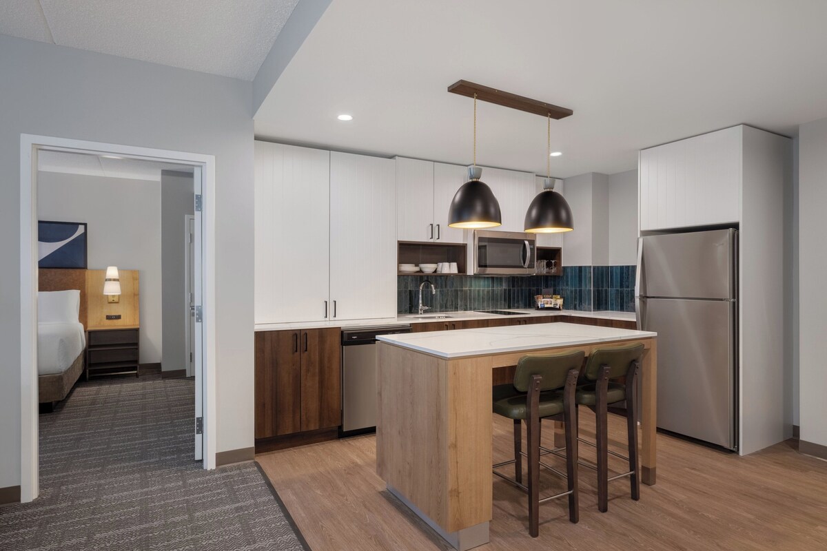 A modern kitchen with a central island, stainless steel appliances, and pendant lighting.