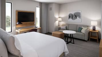 Ein Hotelzimmer mit einem Bett, einem Schreibtisch mit Flachbildfernseher, einer Couch, einem runden Tisch und zwei Lampen.