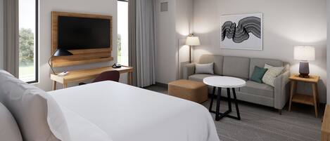 Habitación de hotel con cama, escritorio con televisor de pantalla plana, sofá, mesa redonda y dos lámparas.