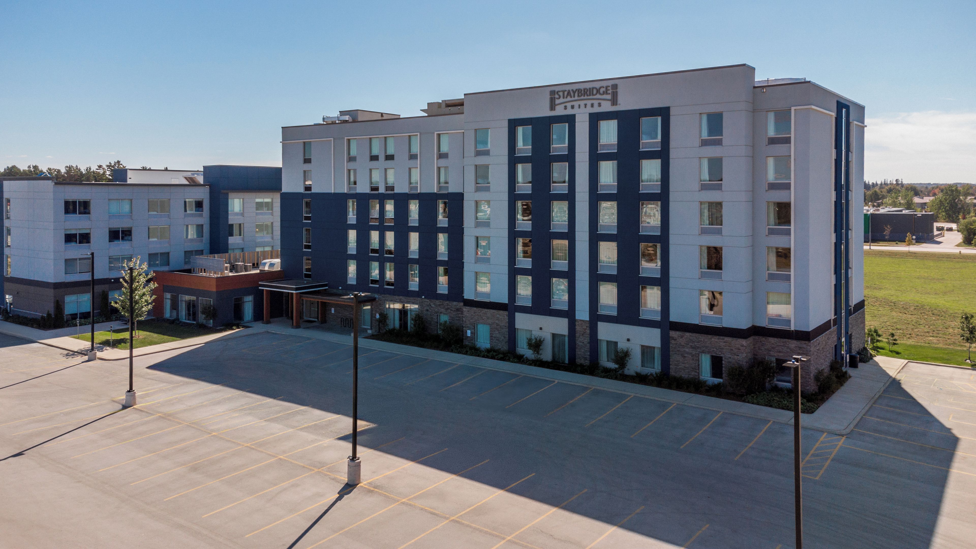 A multi-story hotel with a modern design, featuring a parking lot in front.