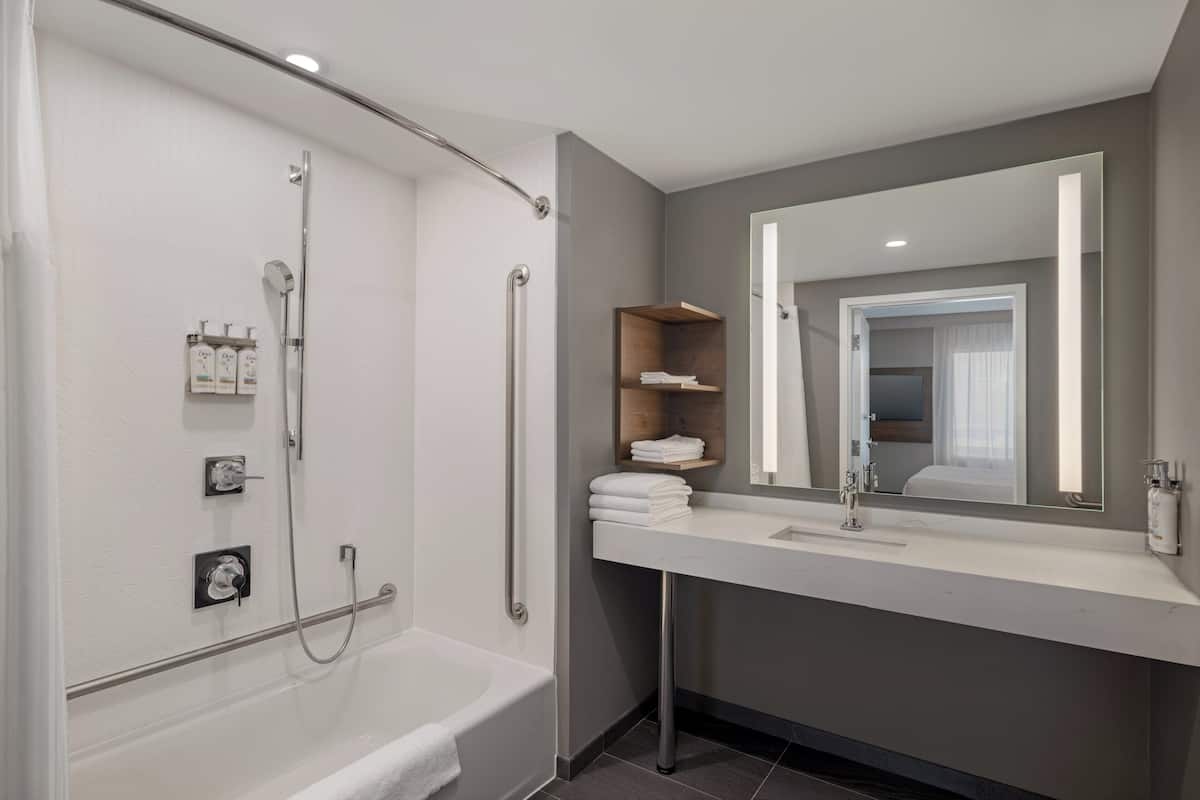 A modern bathroom with a bathtub, a shower, a sink, and a mirror.