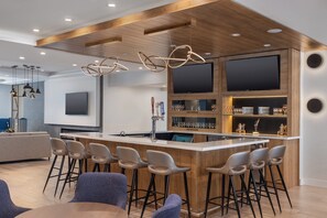 A modern kitchen with a central island, bar stools, and a large flat-screen TV mounted on the wall. - Staybridge Suites Port Elgin by IHG (Saugeen Shores)