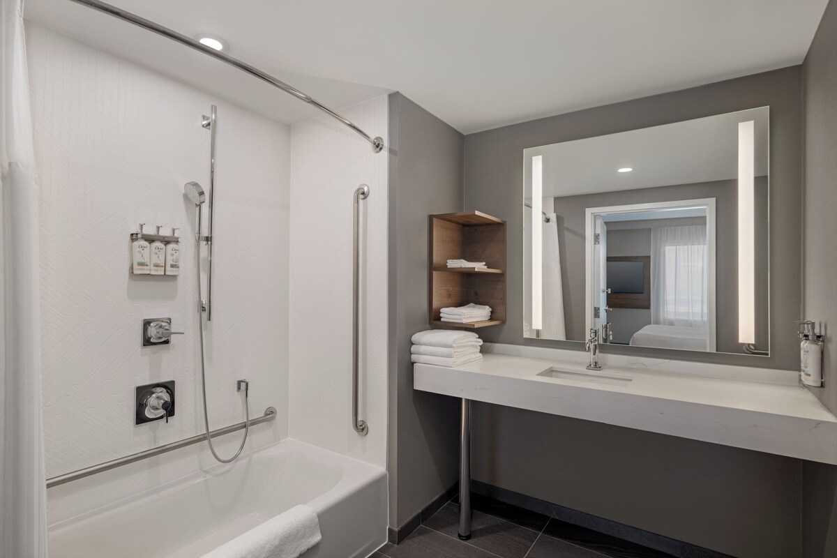 A modern bathroom with a bathtub, a shower, a sink, and a mirror.