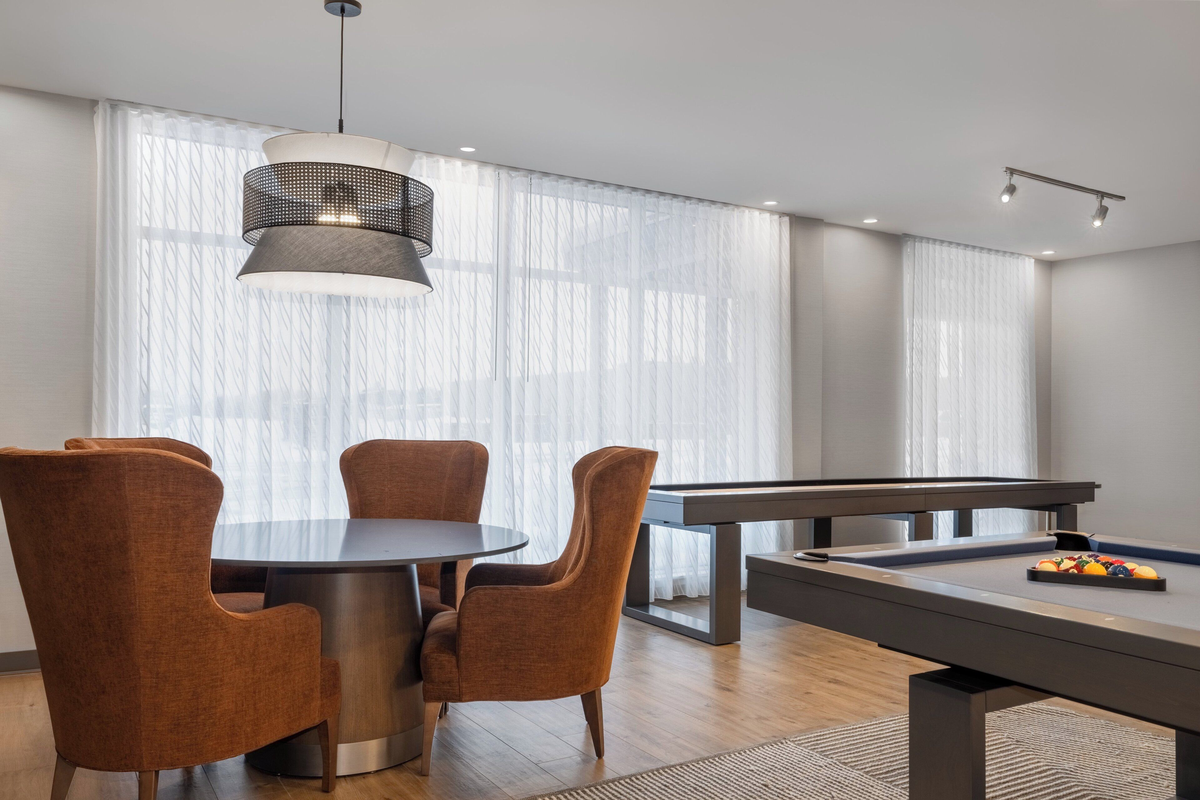 Une pièce moderne équipée d’une table de billard, d’une table à manger ronde avec quatre chaises et d’un luminaire suspendu.