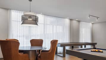 Une pièce moderne équipée d’une table de billard, d’une table à manger ronde avec quatre chaises et d’un luminaire suspendu.