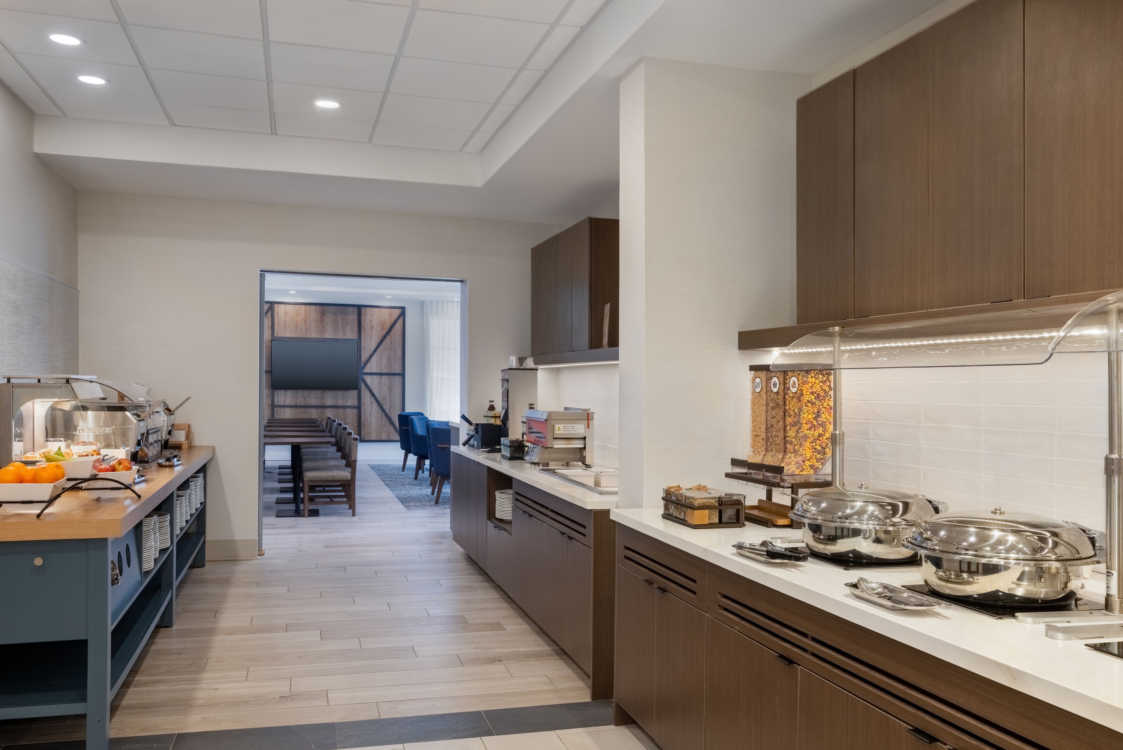 A modern kitchen with a breakfast bar, wooden cabinets, and a built-in oven.
