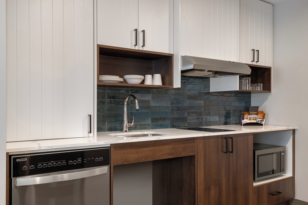 A modern kitchen with white cabinets, a stainless steel dishwasher, a microwave, and a built-in oven.