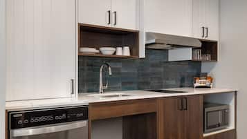 A modern kitchen with white cabinets, a stainless steel dishwasher, a built-in oven, and a tiled backsplash.