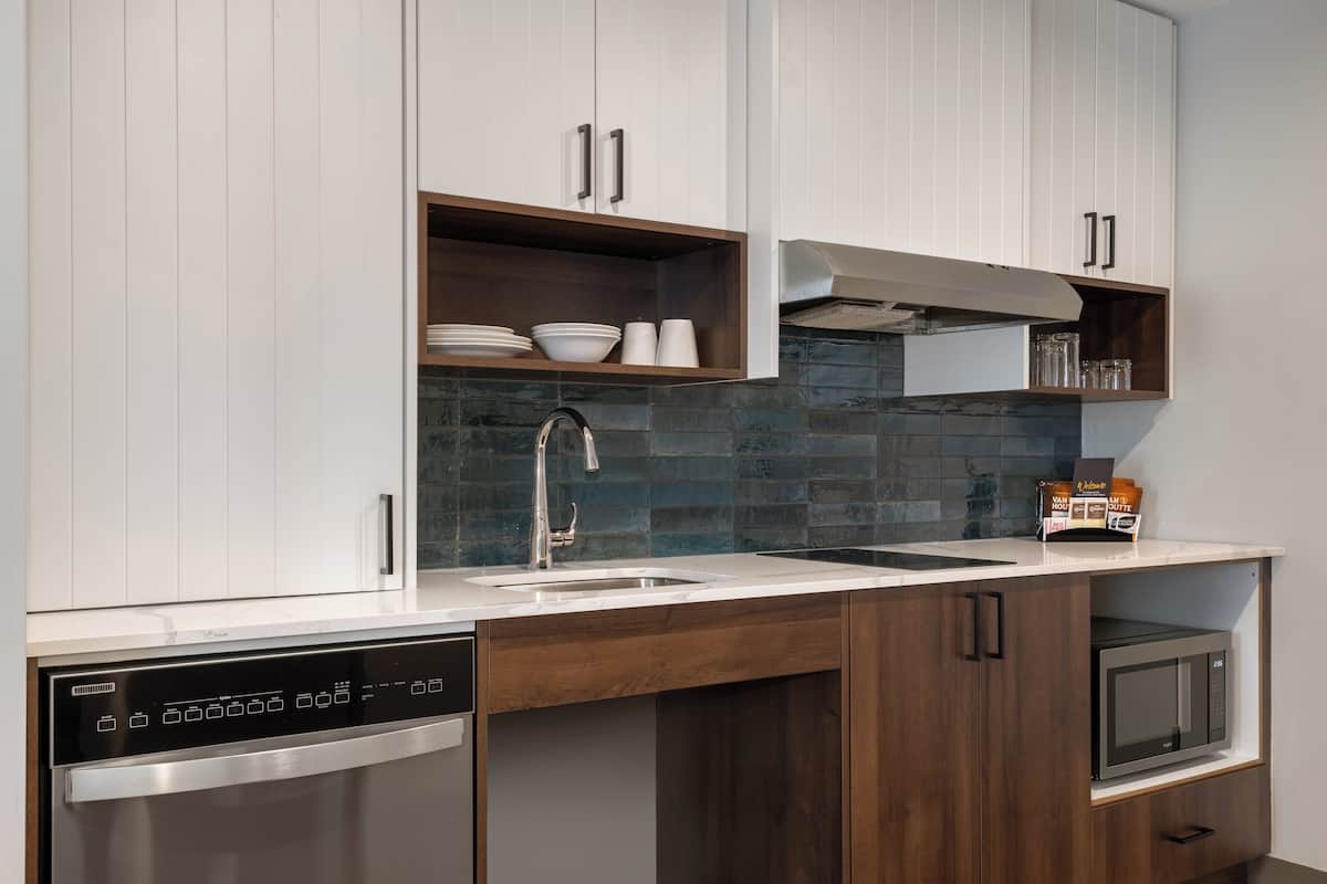 A modern kitchen with white cabinets, a stainless steel dishwasher, a microwave, and a built-in oven.