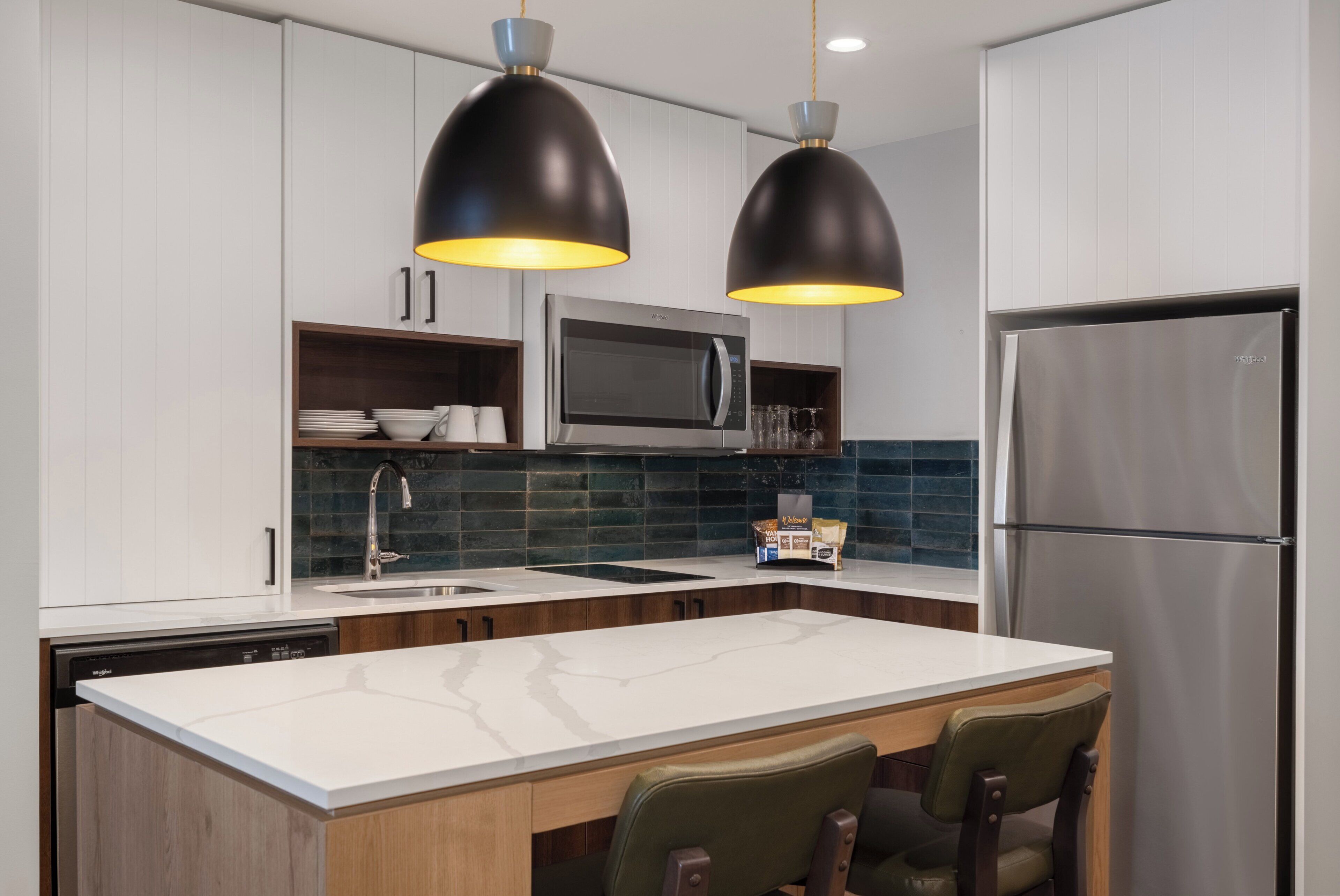 A modern kitchen with white cabinets, a stainless steel refrigerator, a microwave, and a coffee maker.
