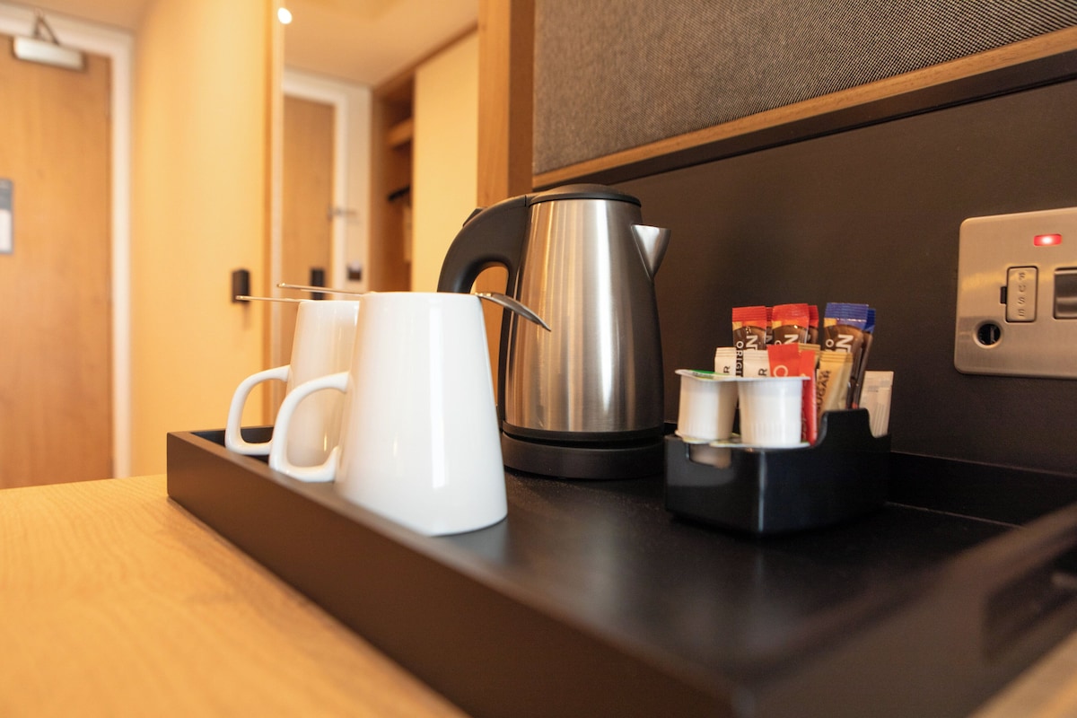 Un comptoir de cuisine avec une machine à café, des tasses et des sachets de sucre.