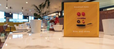 A breakfast menu card on a table with a clear view of the menu items and the restaurant's interior.