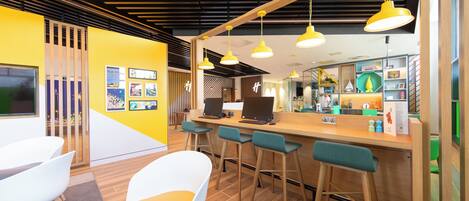 A modern bar area with wooden flooring, yellow walls, and bar stools.