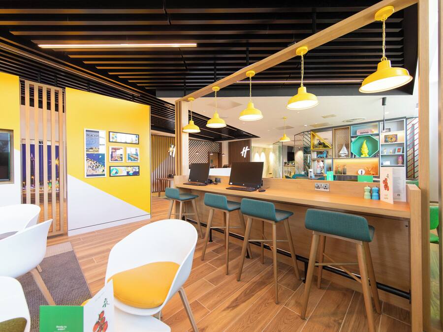 Un área de bar moderna con suelo de madera, paredes amarillas y taburetes.