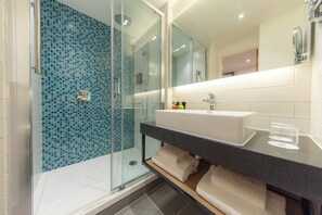 A modern bathroom with a glass shower enclosure, a white sink, and a mirror above it.