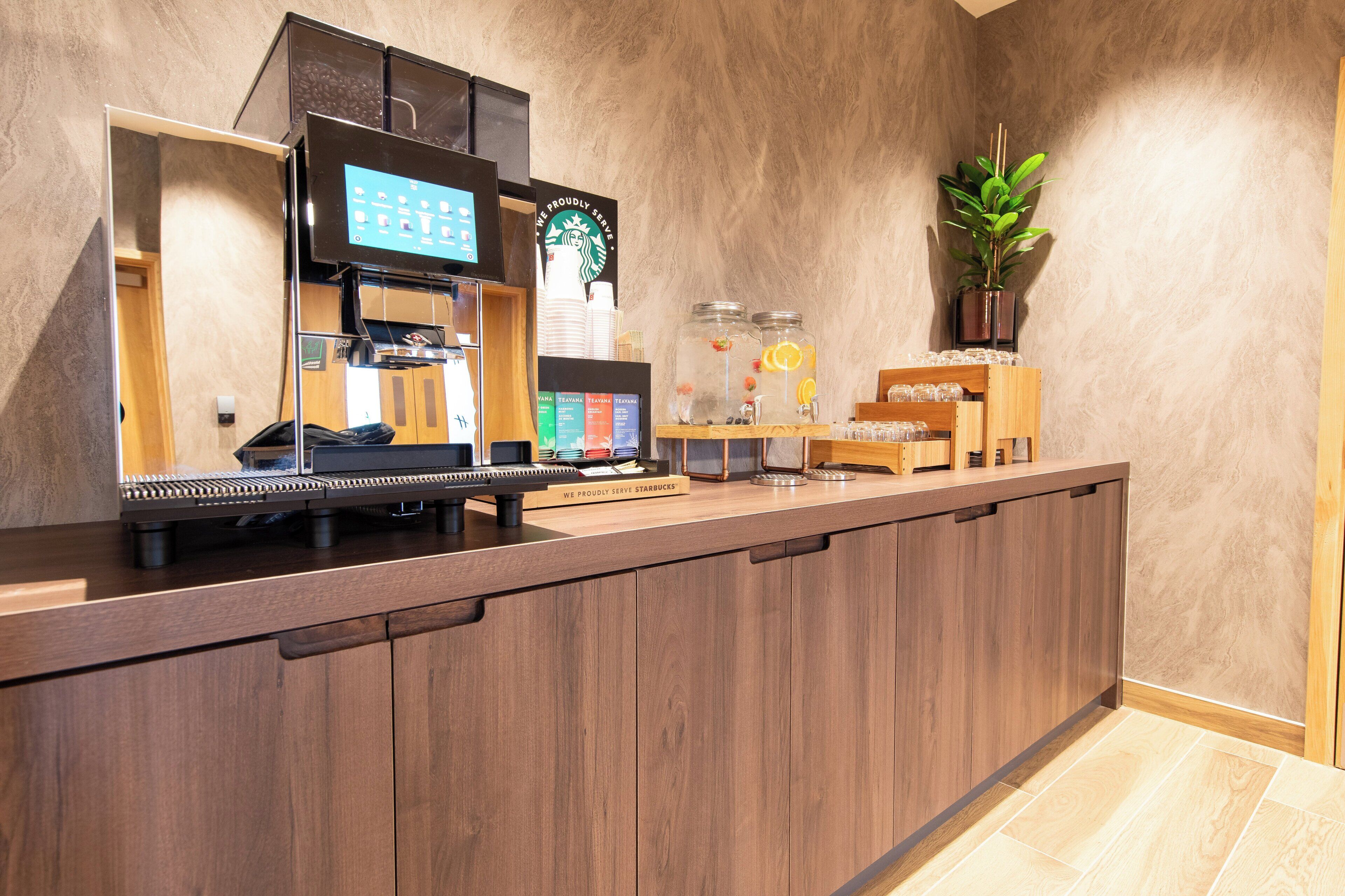 A Starbucks coffee shop counter with an espresso machine, a digital menu board, and a variety of drink options.