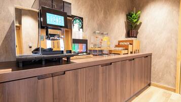 A Starbucks coffee shop counter with an espresso machine, a digital menu board, and a variety of drink options.
