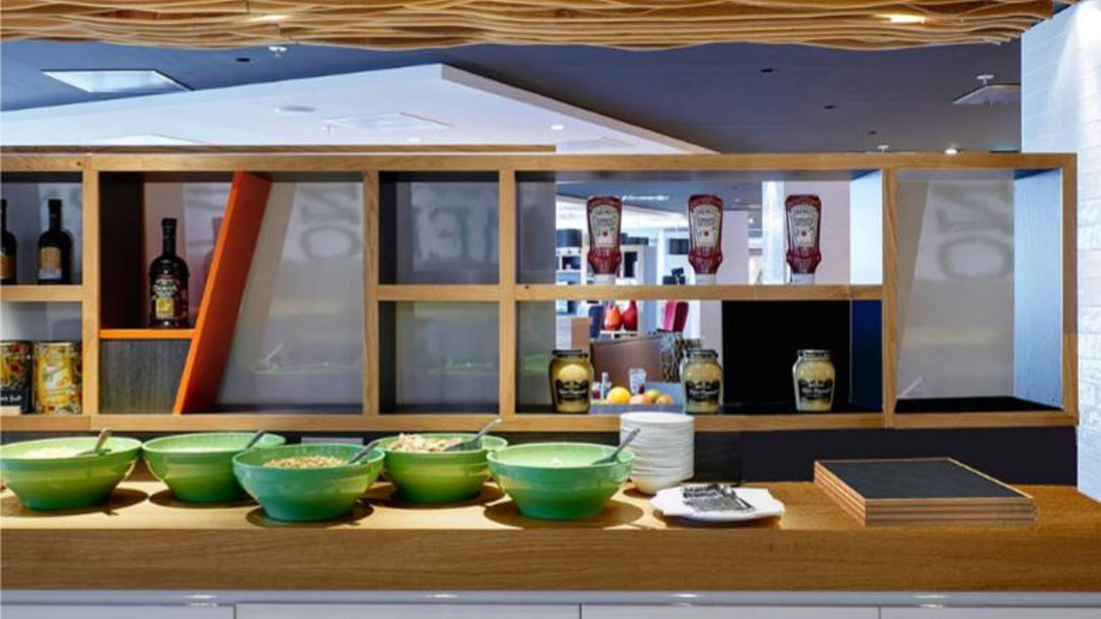 A modern kitchen with wooden cabinets, green bowls, and various kitchen items.