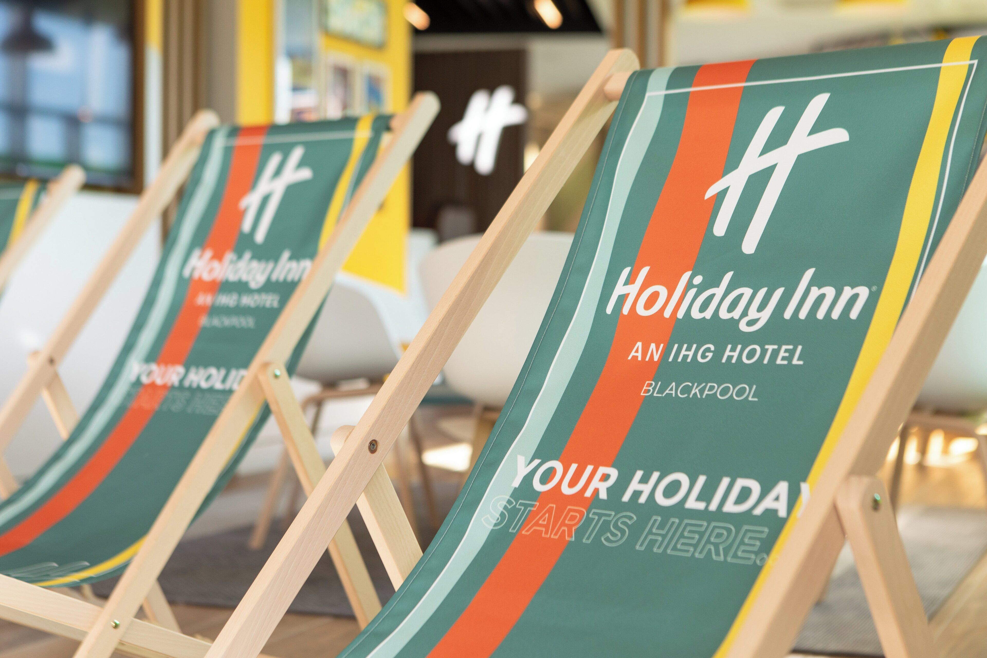 Filas de sillas de playa con la marca 'Holiday Inn', lo que indica un entorno hotelero.