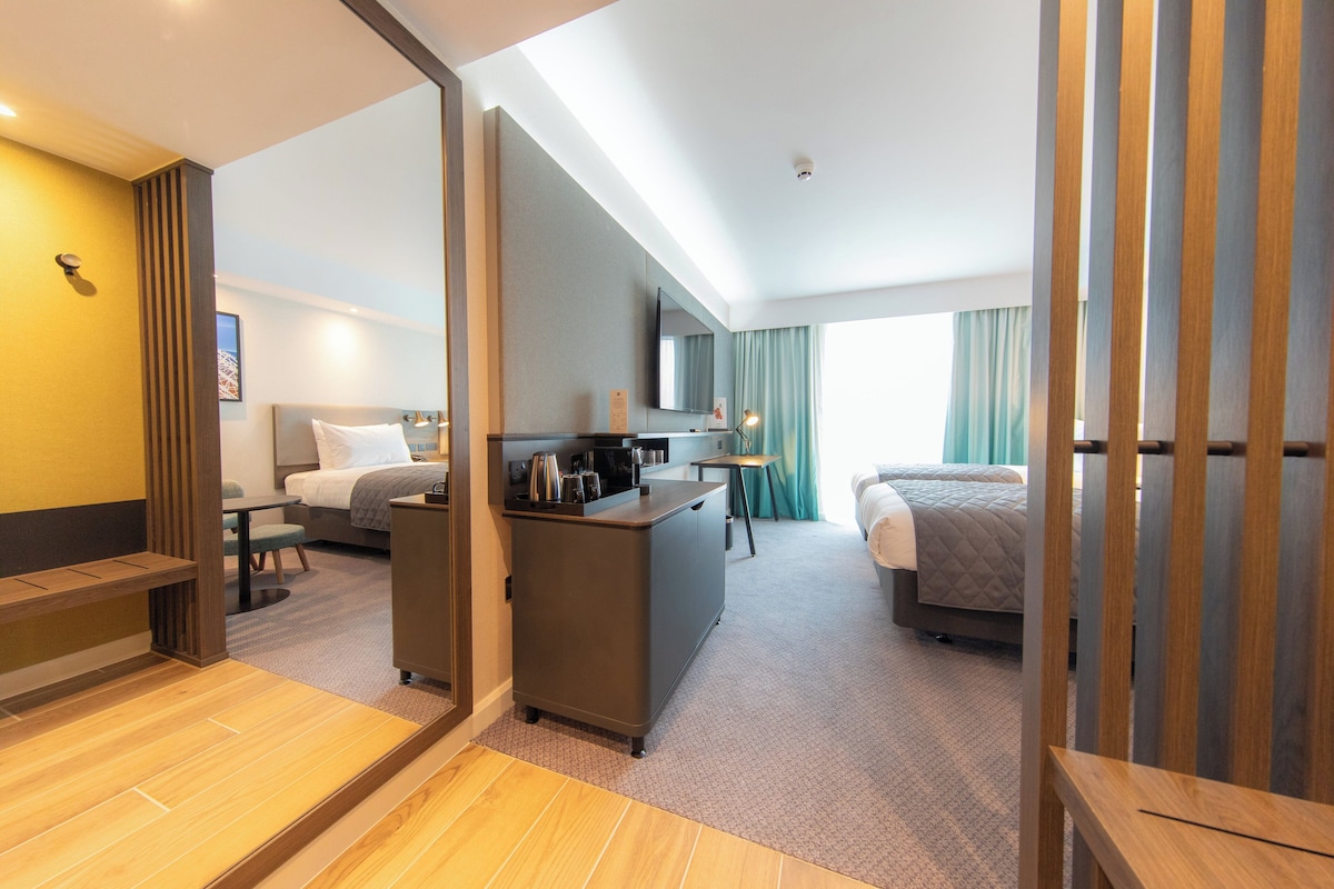 Une chambre d’hôtel comprenant un lit, un bureau, une chaise, une petite table et un téléviseur.