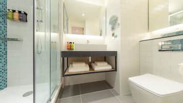 Een moderne badkamer met een douchecabine van glas, een wit toilet en een wastafel met spiegel.