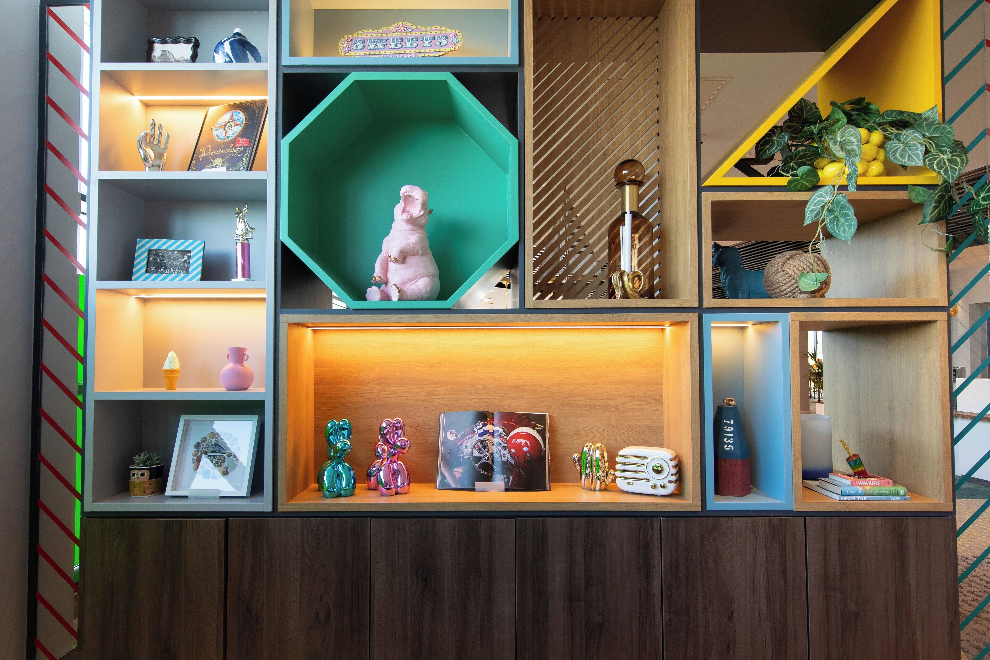 Uma estante com vários níveis exibindo objetos decorativos, como figuras, livros e uma moldura com fotografia.