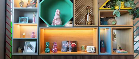 Uma estante com vários níveis exibindo objetos decorativos, como figuras, livros e uma moldura com fotografia.