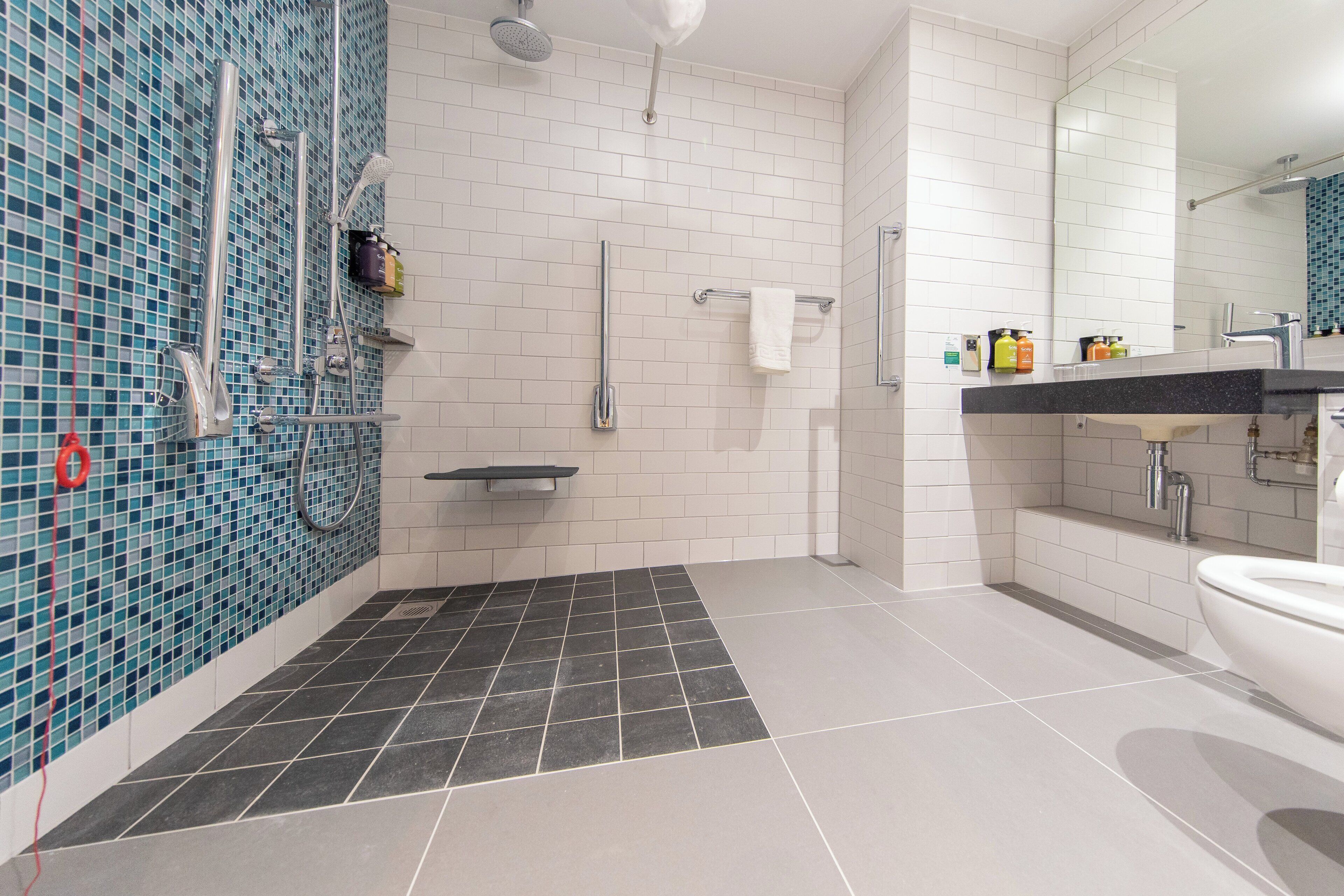A modern bathroom with a shower, sink, and toilet.
