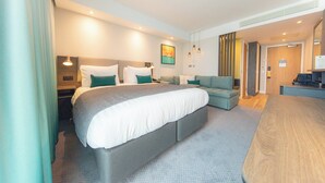 A modern hotel room with a large bed, a sofa, a desk, and a television. - Holiday Inn Blackpool by IHG (Blackpool)