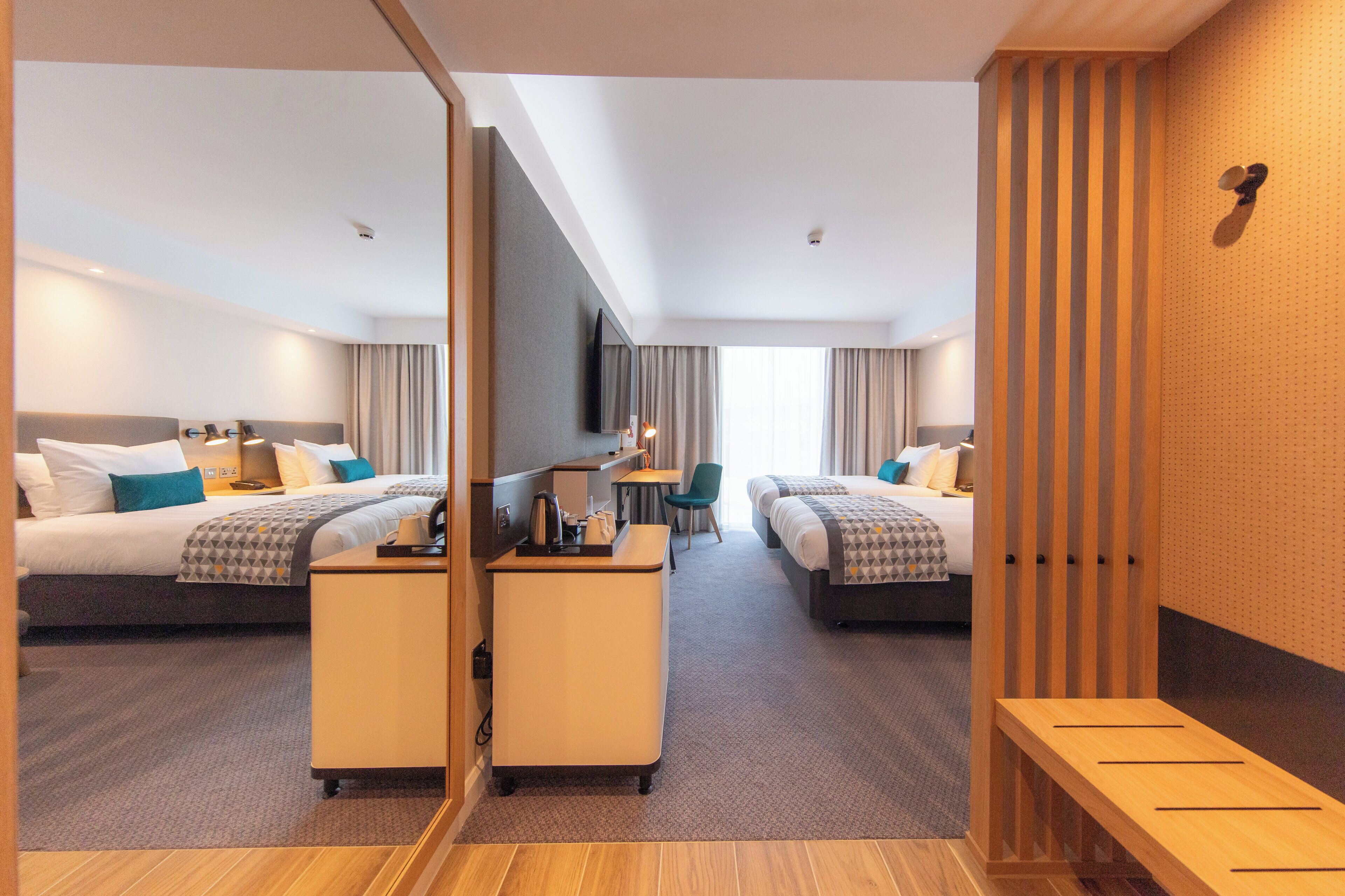A hotel room with two beds, a desk, and a seating area.