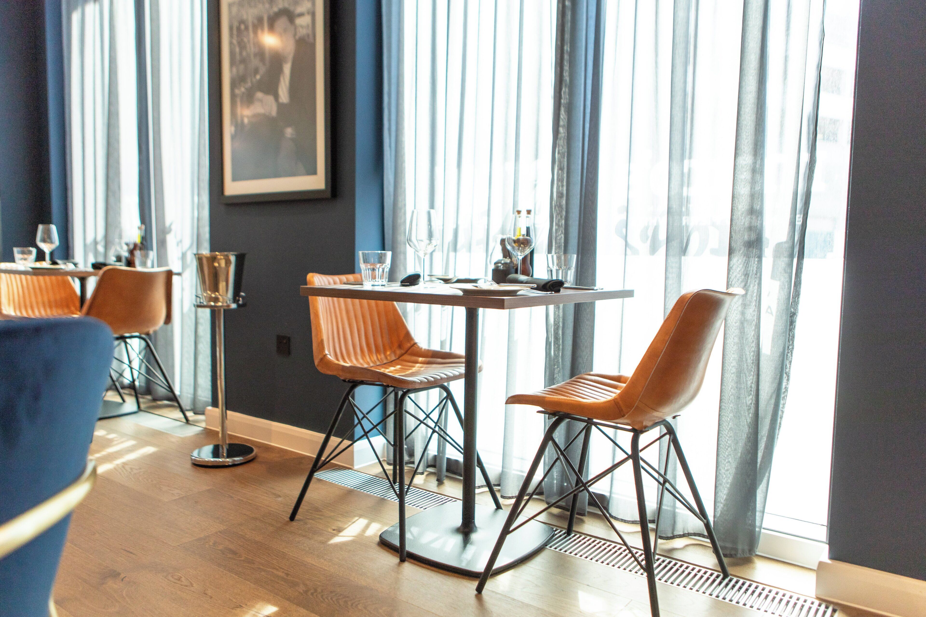 A dining area with a table set for two, two chairs, and a tall glass stand.