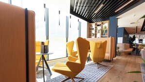 A modern interior with yellow chairs, a wooden table, and a patterned rug.