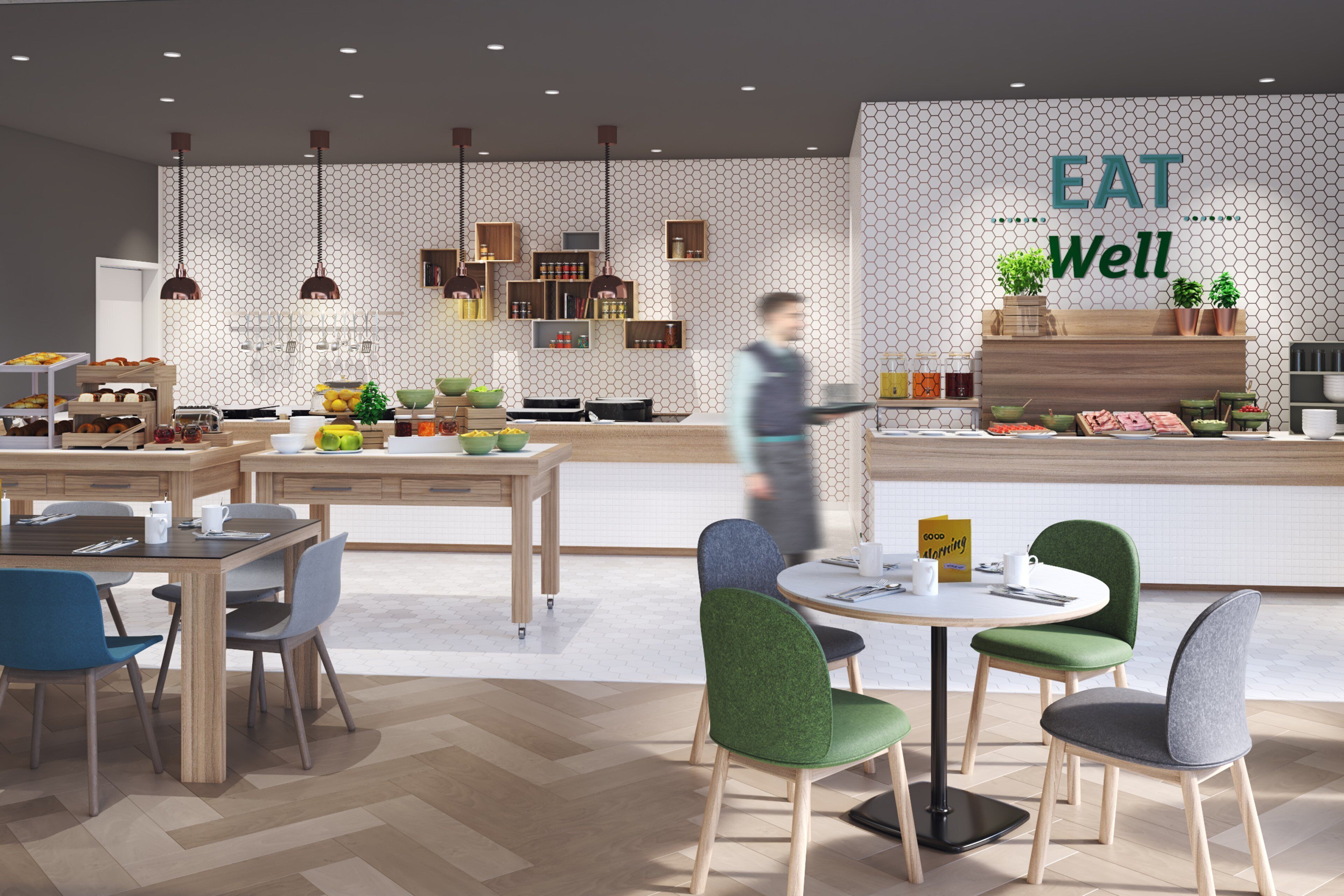 A modern cafe with a hexagonal patterned wall, wooden furniture, and a counter displaying food and drinks.