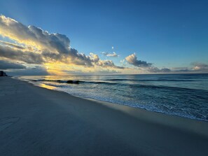 A beach with a clear sky and sunlight reflecting on the water.