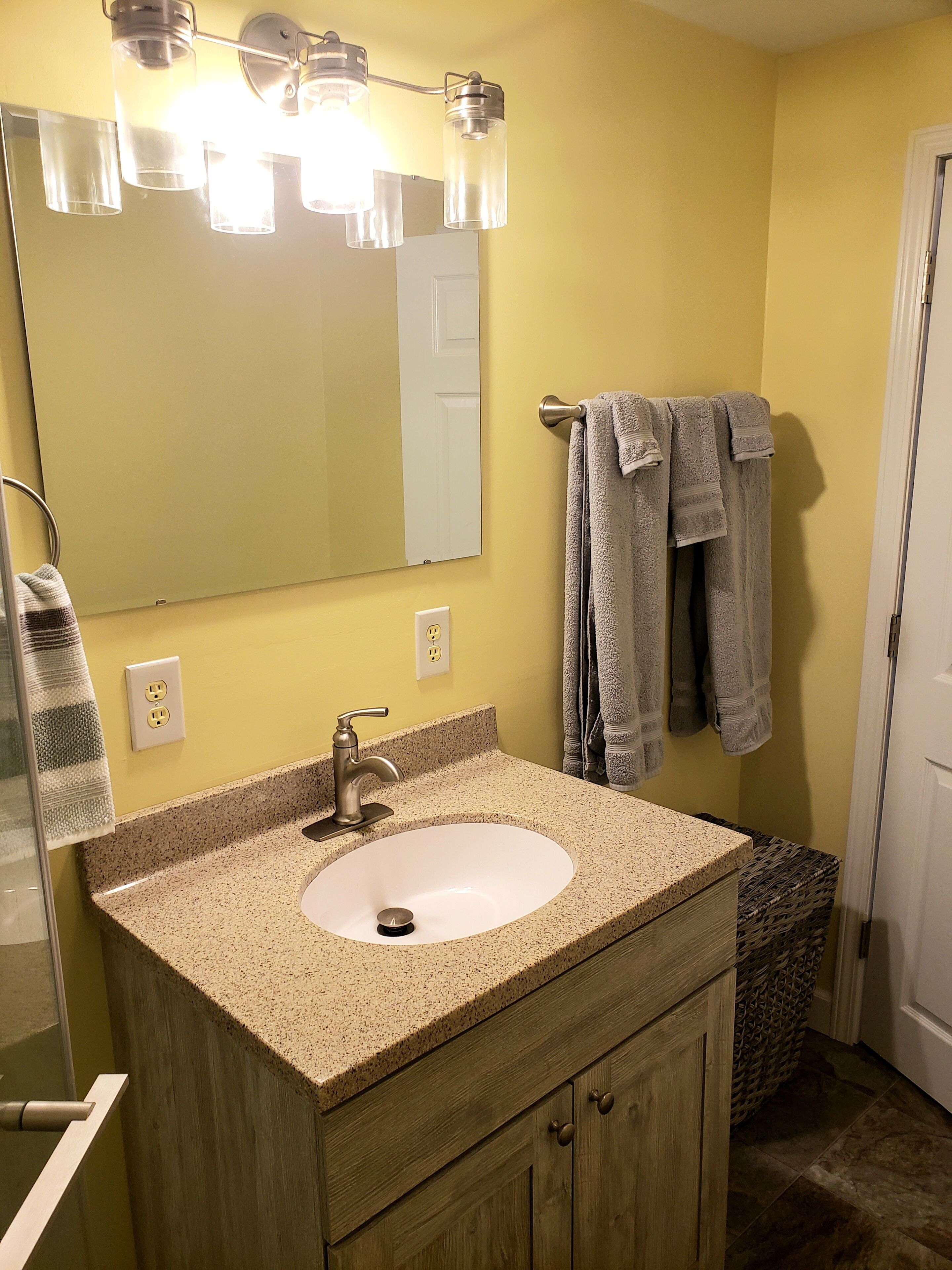 A bathroom with a granite countertop sink, a mirror, and two towels hanging on a towel rack.