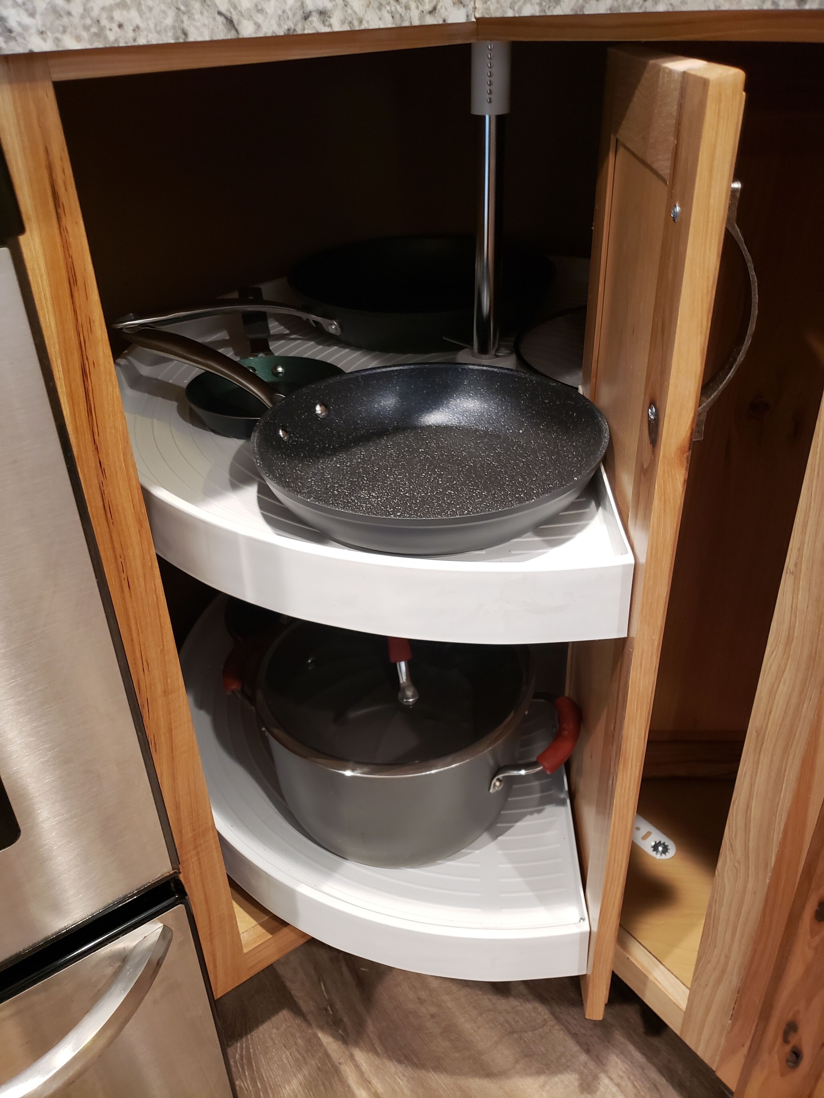 A kitchen with a stove, a frying pan, and a pot on a white shelf.
