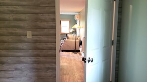 Una habitación con paneles de madera, una puerta blanca y una cama con una lámpara.