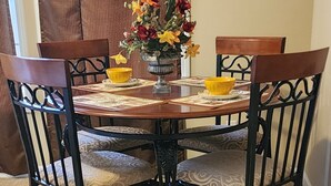A dining table with four chairs, a vase with flowers, and a yellow bowl on a carpeted floor. - Mountain Home,  PET FRIENDLY!!  Anderson Farms@Fall Creek Falls State Park  (Pikeville)