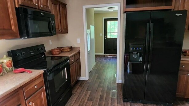 A kitchen with wooden cabinets, a black refrigerator, a microwave, and a stove. - Mountain Home,  PET FRIENDLY!!  Anderson Farms@Fall Creek Falls State Park  (Pikeville)