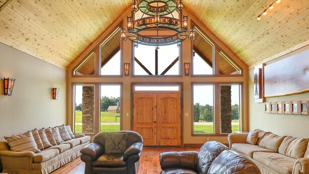 A spacious living room with high ceilings, large windows, and a fireplace. - The Bunkhouse Retreat /Sleeps 15/7BR/5BA/4 Private Acres (Kings Mountain)