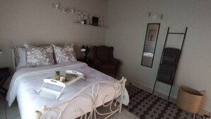A neatly arranged bedroom with a bed, bedside table, chair, and a mirror. - Lovely 1 bedroom Loft in the Heart of Walvisbay. (Walvis Bay)